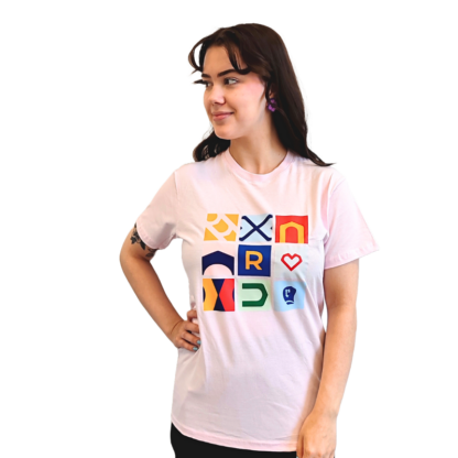 Kuvassa vaaleanpunainen Rauman brändi t-paita, jossa on kuvituksena on merikaupunkilogo ja Kaupungin porttilogo eri muodoissa